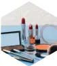 Zestaw kosmetyków na biurku: szminki, pędzle, róż i zestaw cieni – nawiązanie do branży beauty.
